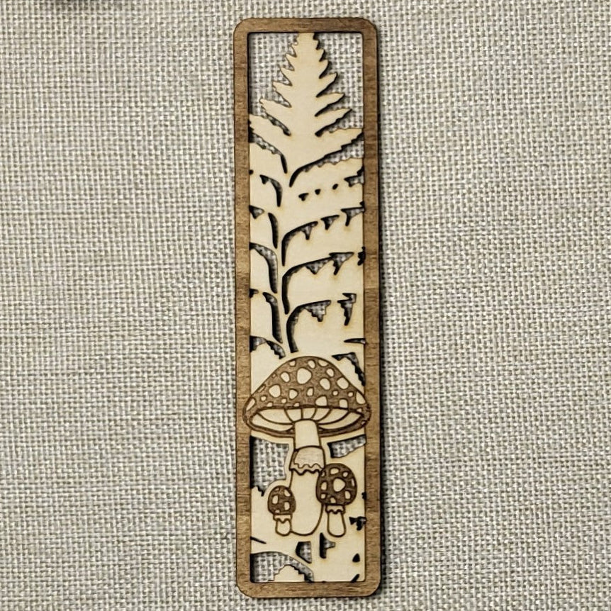 Wooden bookmark with mushroom design on a textured fabric background