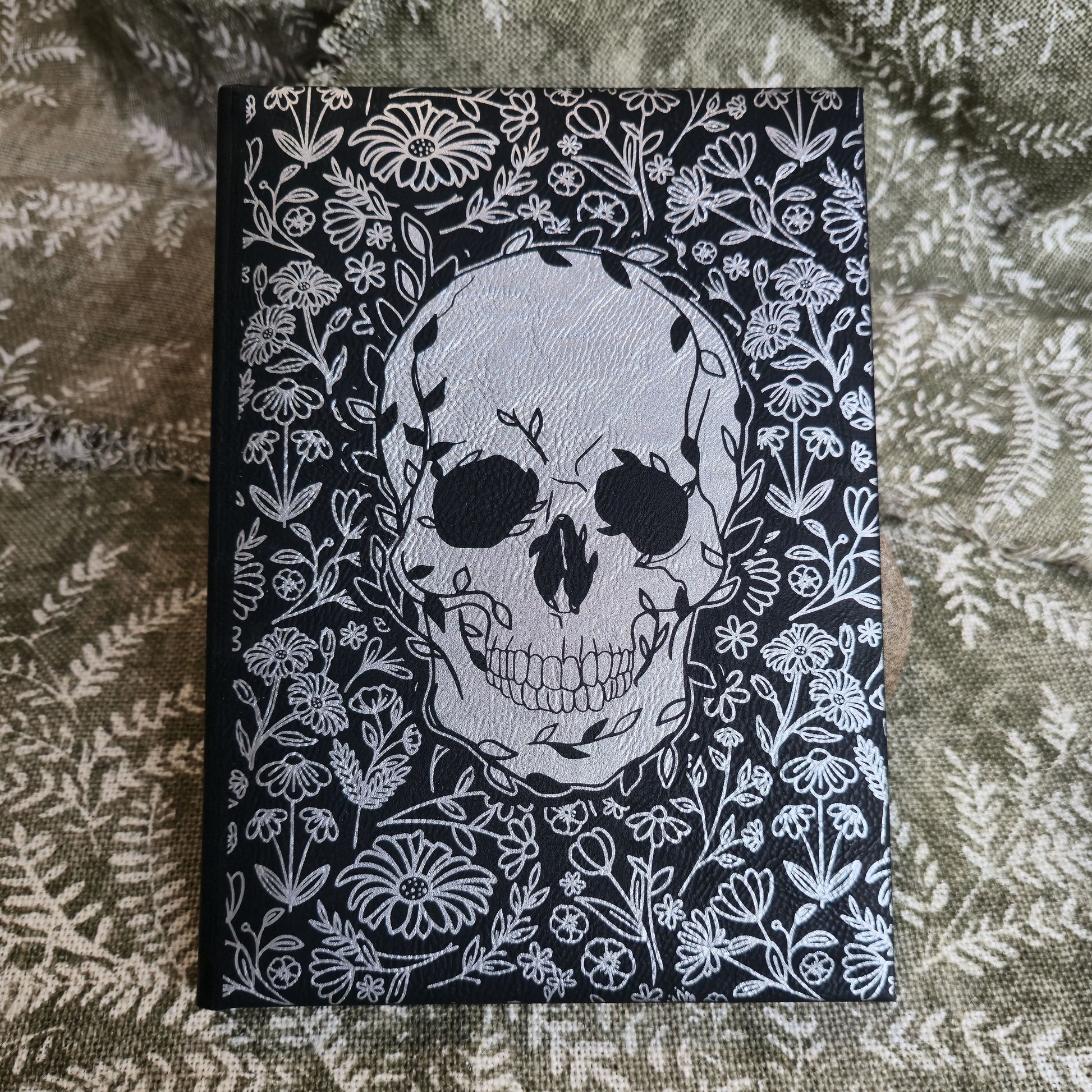 Notebook with skull and floral design on a textured fabric background
