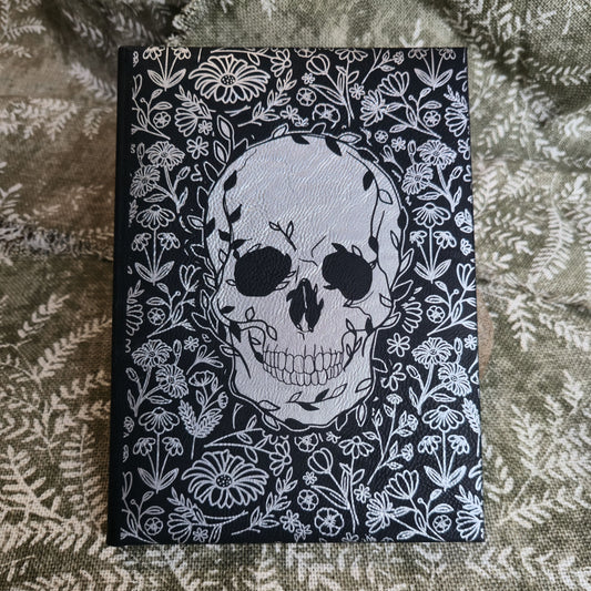Notebook with skull and floral design on a textured fabric background