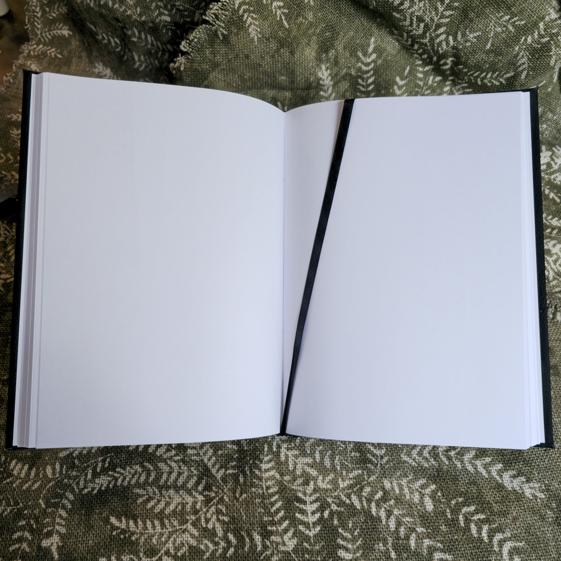 Open notebook with blank pages on a green fabric background