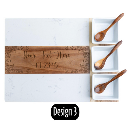 Wooden cutting board with engraved text and three wooden spoons on a marble surface.